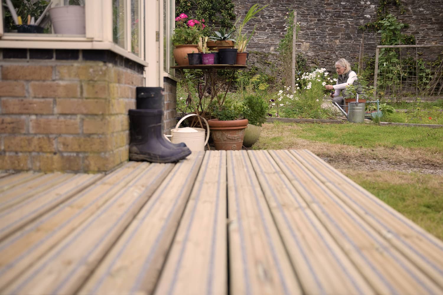 Woman gardening near summerhouse with Gripsure non-slip decking
